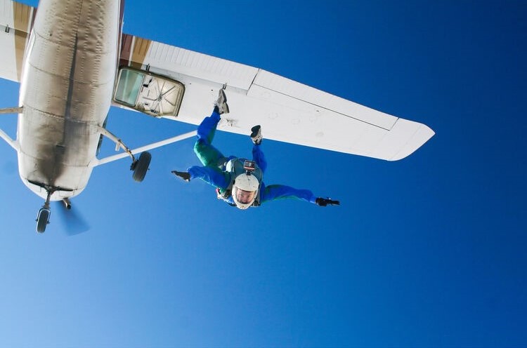 man jumping out of airplane with action camera head mount on helmet