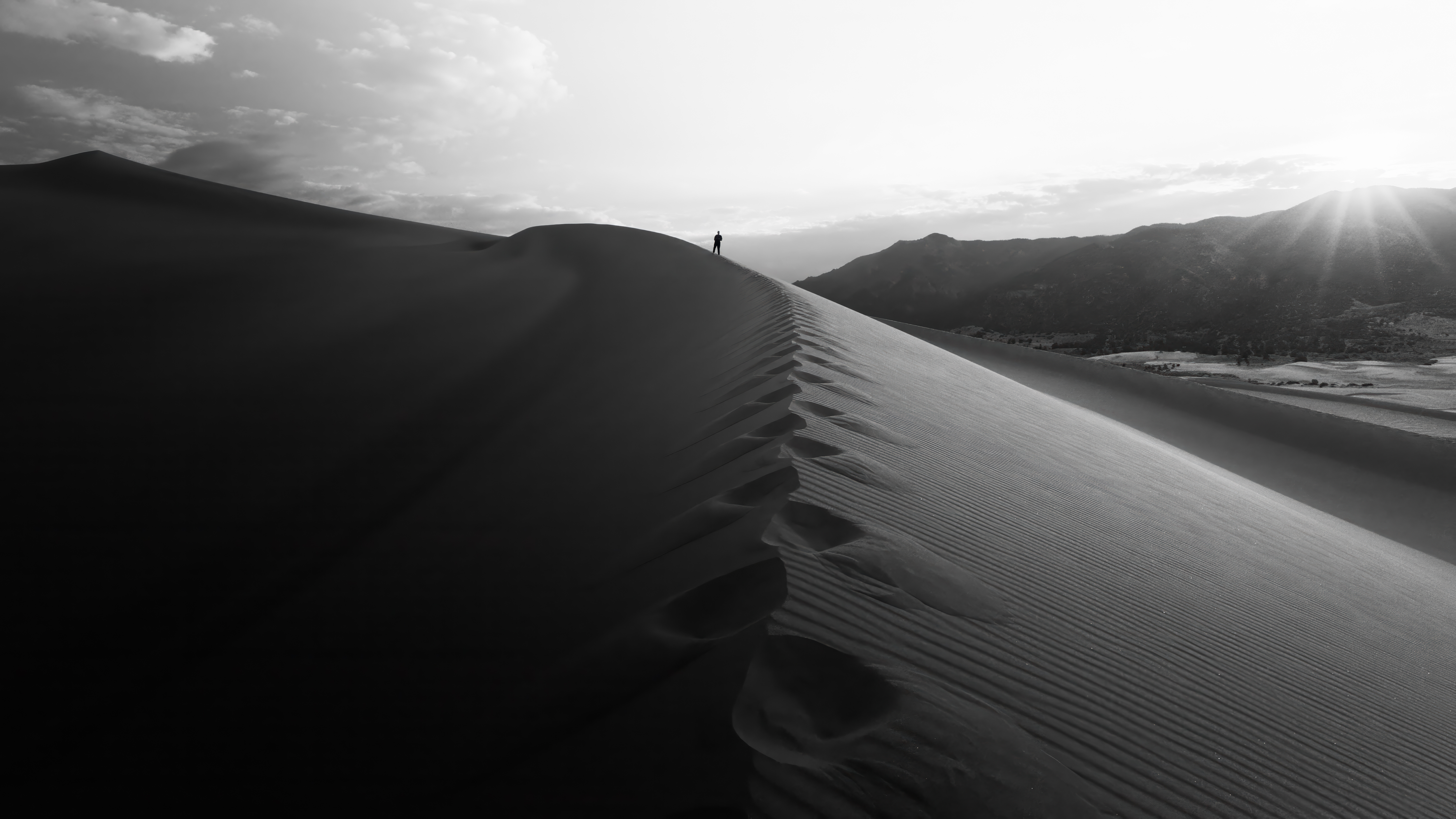 Black and white image of a person on top of a desert top