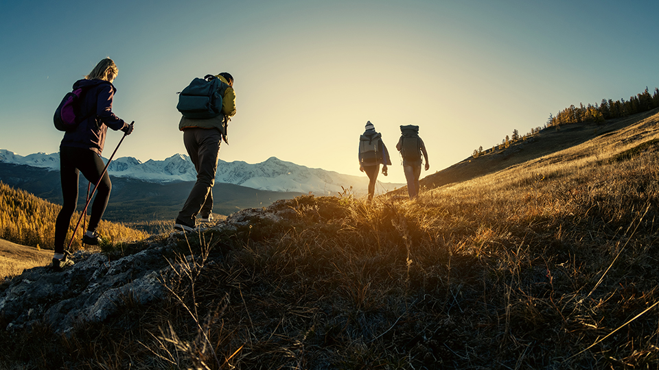 Group of hikers walks in mountains at sunset Group of hikers walks in mountains at sunset