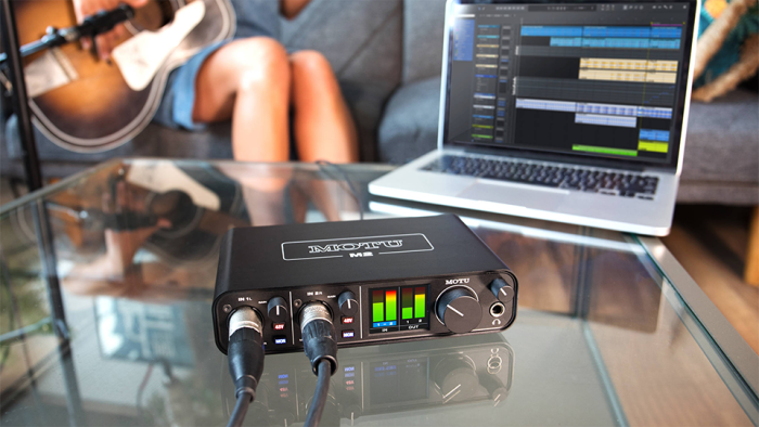 Person playing guitar and recording music using an audio interface and laptop Person playing guitar and recording music using an audio interface and laptop
