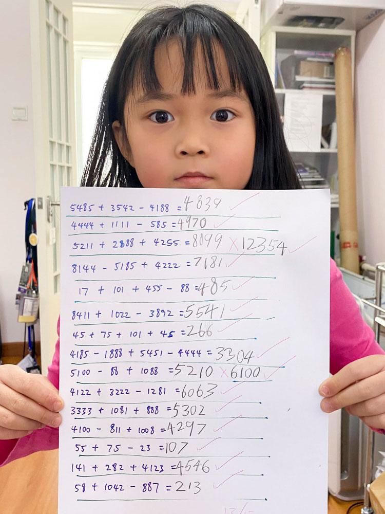 Little Chow, 6, displays a page of her math calculations. Chow and his wife have home schooled both of their children for nearly two months by giving them regular work assignments.
