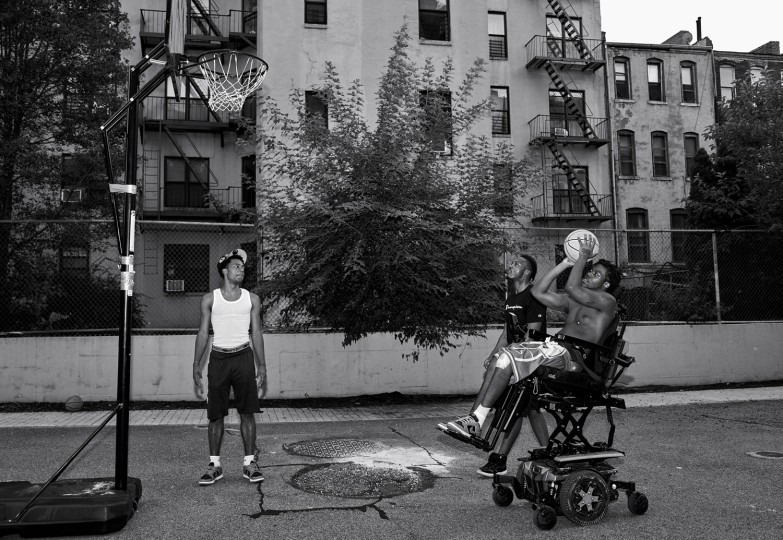 Malik shoots some hoops from his wheelchair. Typically, his only exercise is a daily pushup regime in bed.