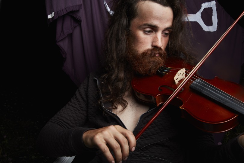 Tree Planter Clayton Gray playing his violin at camp after a long day, 2016