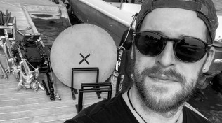 Behind the scenes view of Mike in Abu Dhabi unloading gear from a boat on a private island before a shoot with Juan Carlos, former King of Spain, 2023