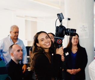 NPR staff videographer Keren Carrion poses with her camera set-up during an NPR Tiny Desk Concert, November 2025.