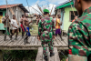 Members of the Indonesian National Army (TNI) look on while Asmat men occupy the streets during a raid on the Kaigars, 512/15.