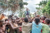 Fr. Vincent Cole is paraded into the jungle by the villagers of Sa-Er, where he will baptize about 90 village children, while incorporating Asmat terms into the Catholic baptism ritual.